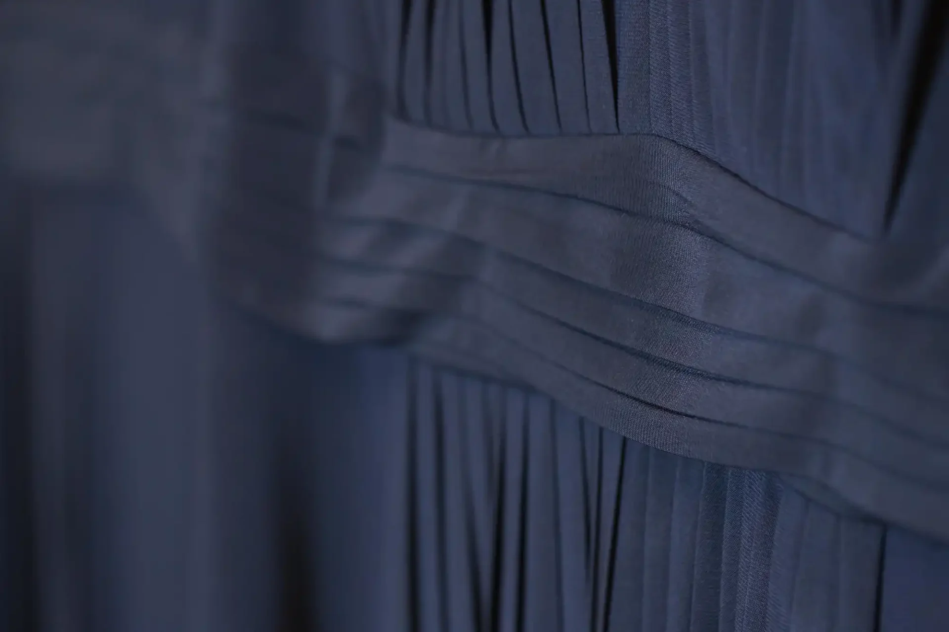 Close-up of a blue garment with detailed pleats and textured fabric.