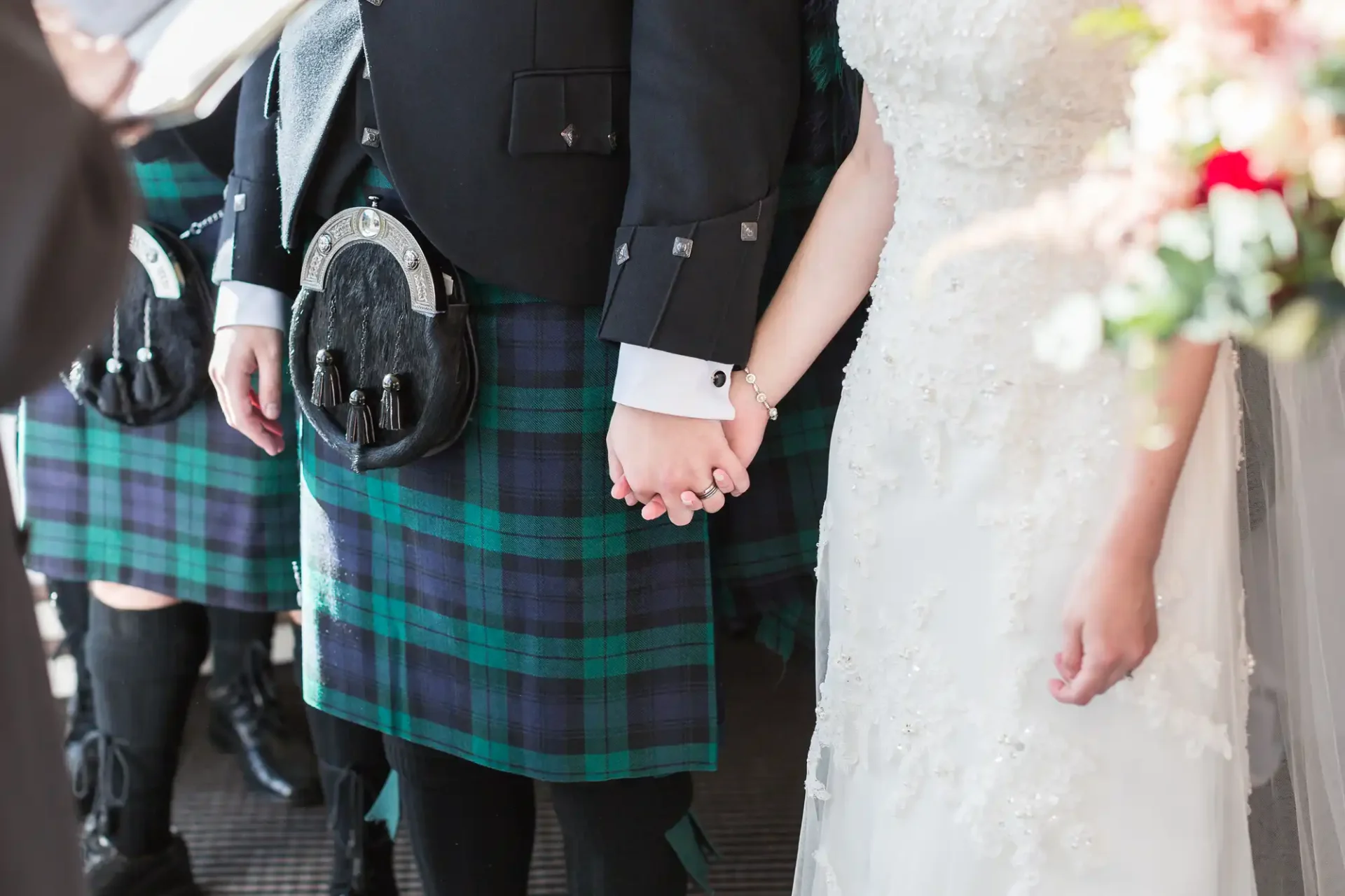 Bride and groom holding hands, the groom in a kilt and sporran, at a wedding ceremony.