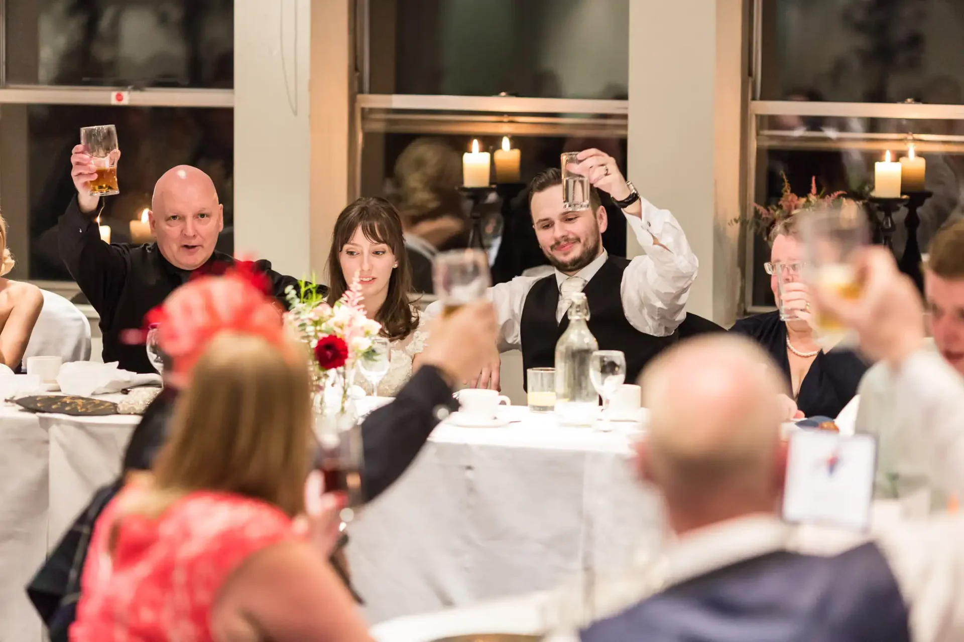 Guests raising their glasses for a toast at a lively banquet hall during a formal event.