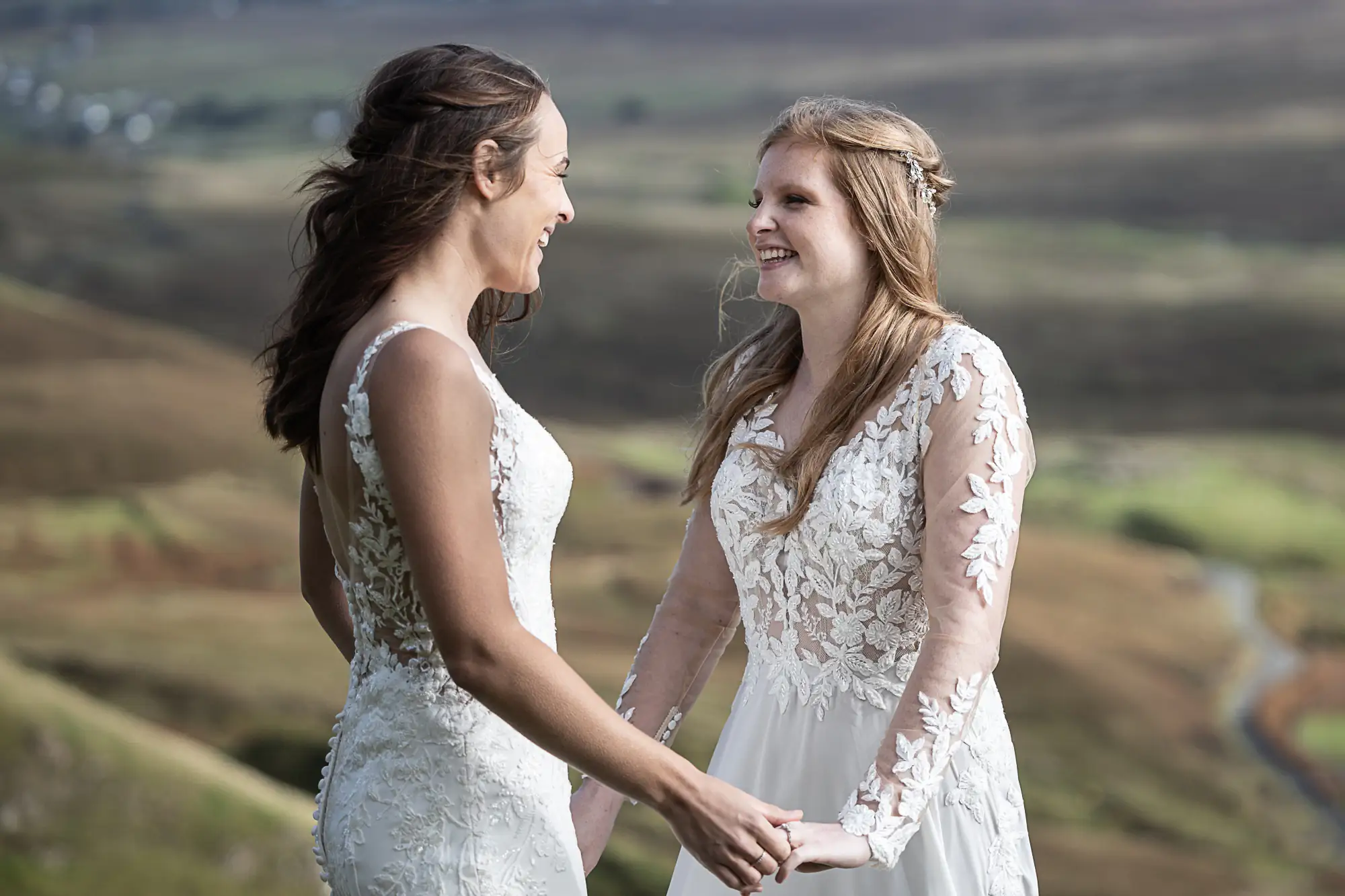 two brides hold hands smiling at each other