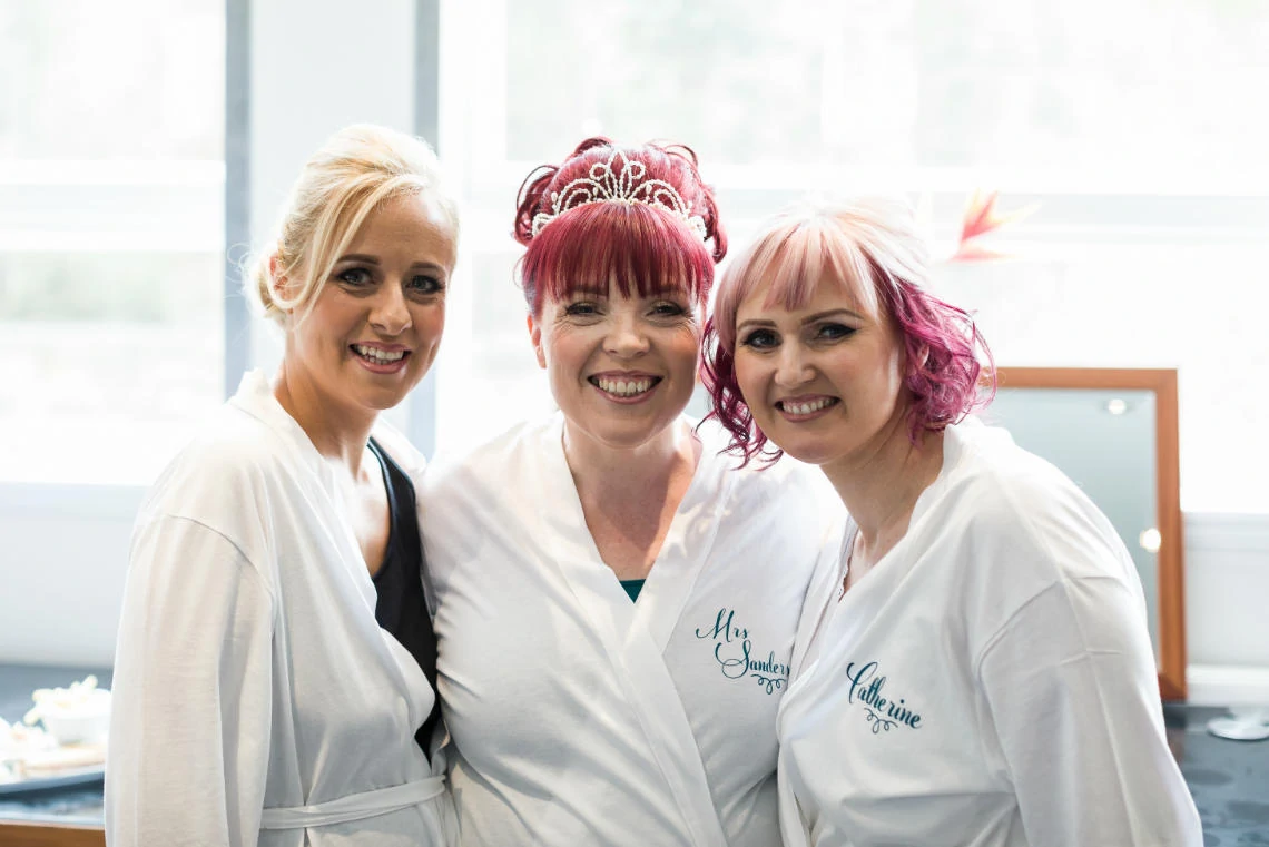 bride and bridesmaids wearing white robes during pre-ceremony preparations