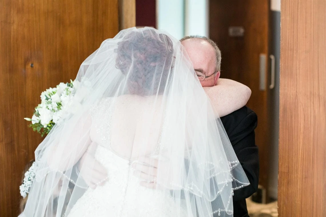 father of the bride embraces his daughter just before they make their way to meet the groom