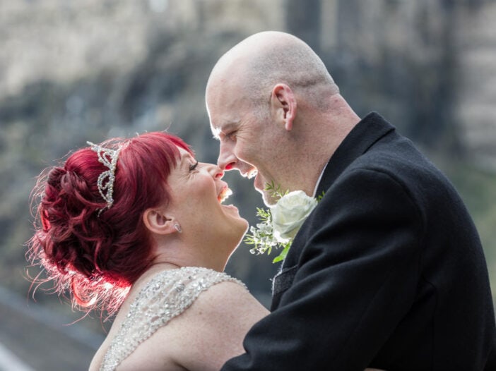 newlyweds touch noses in the Vennel with Edinburgh Castle in the background