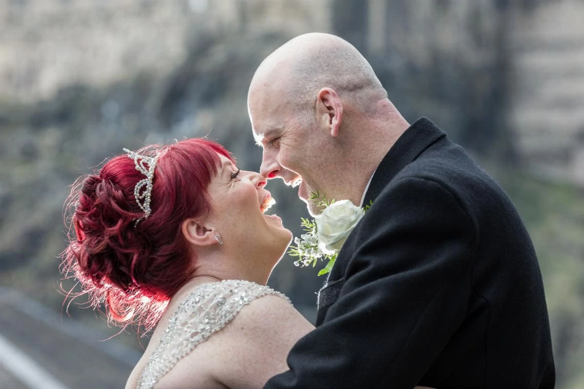 newlyweds touch noses in the Vennel with Edinburgh Castle in the background