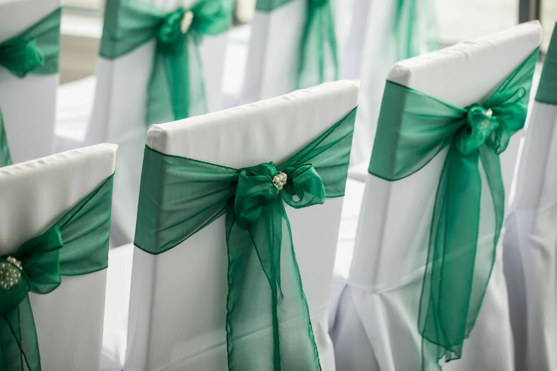 white chair covers and dark green tie-back ribbons