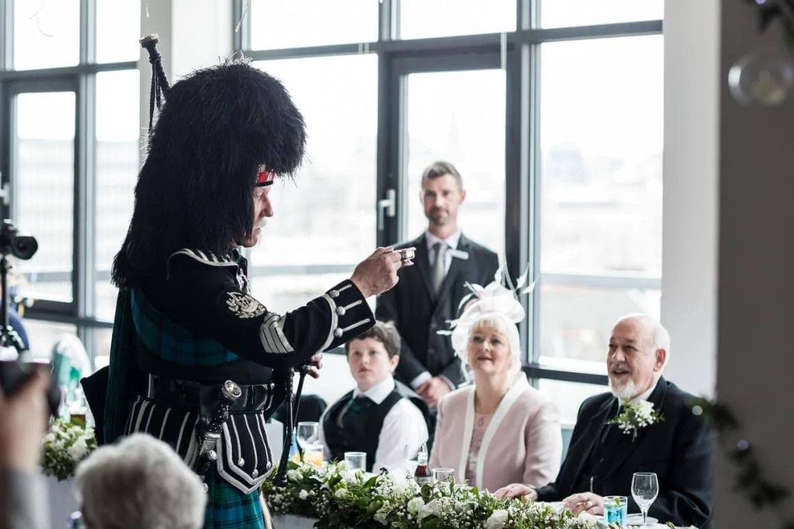 piper toast newlyweds at the top table with a dram