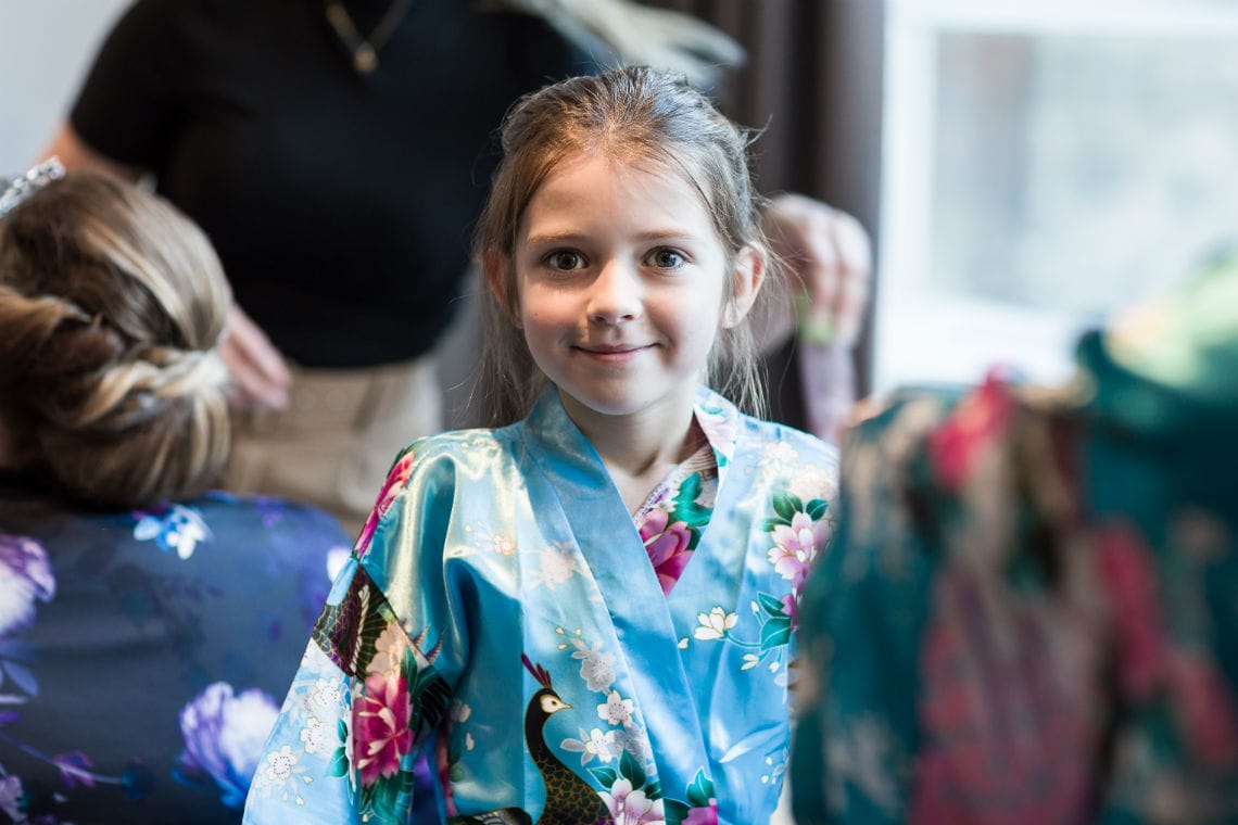 young girl smiling wearing blue silk dressing gown during bridal preparations