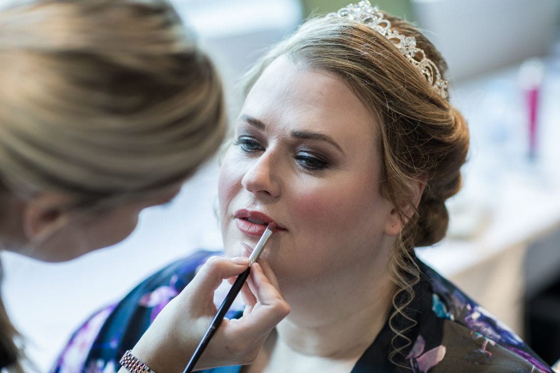 bride getting lipstick applied with brush during bridal preparations