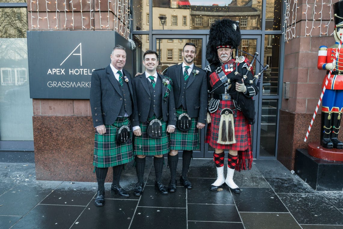groom, father of the groom and bestmand with piper outside the front of the hotel