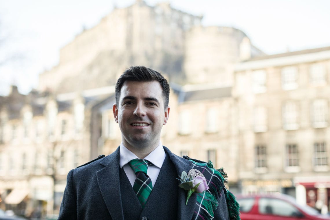 close up portrait shot of groom smiling with Edinburgh Castle in the background