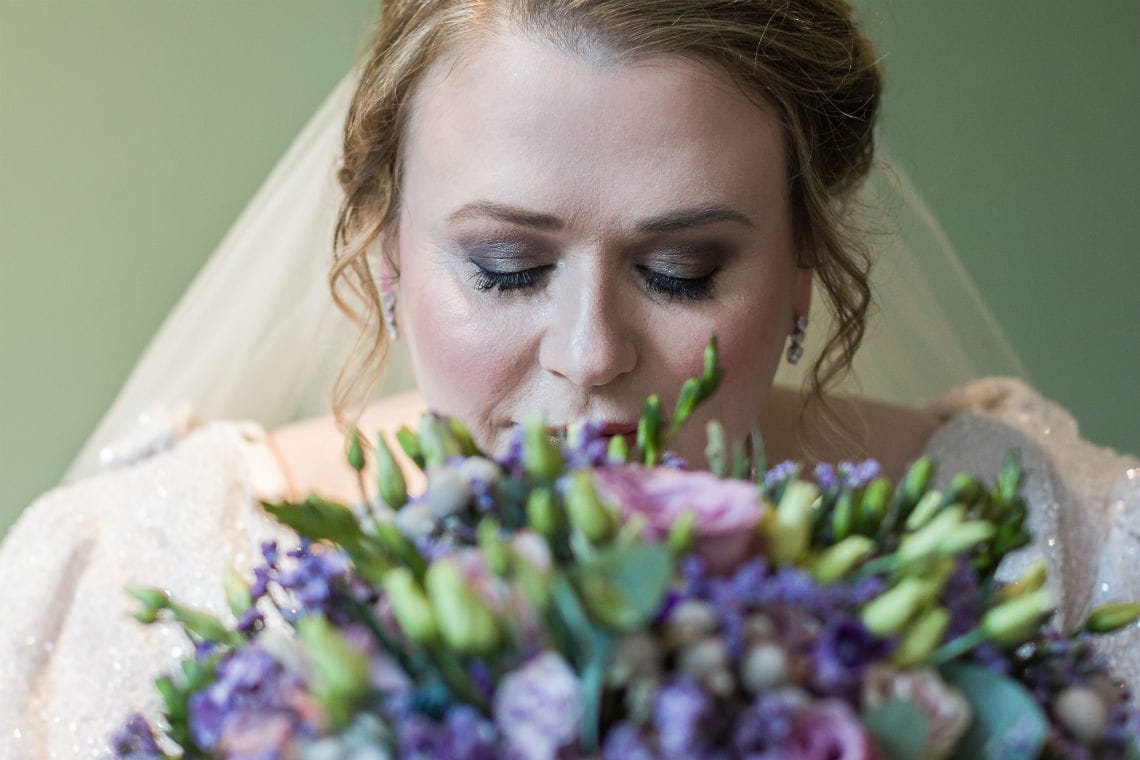 close up shot of bride smelling her bridal bouquet of flowers
