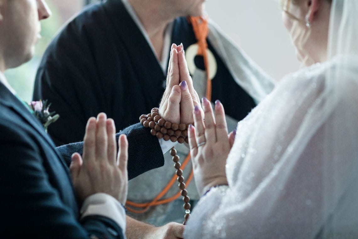 close up photo of bride and grooms hands entwined with beads