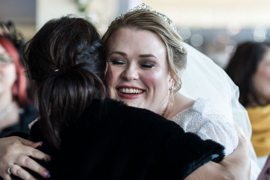 close up photo of bride smiling as she is congratulated by guest