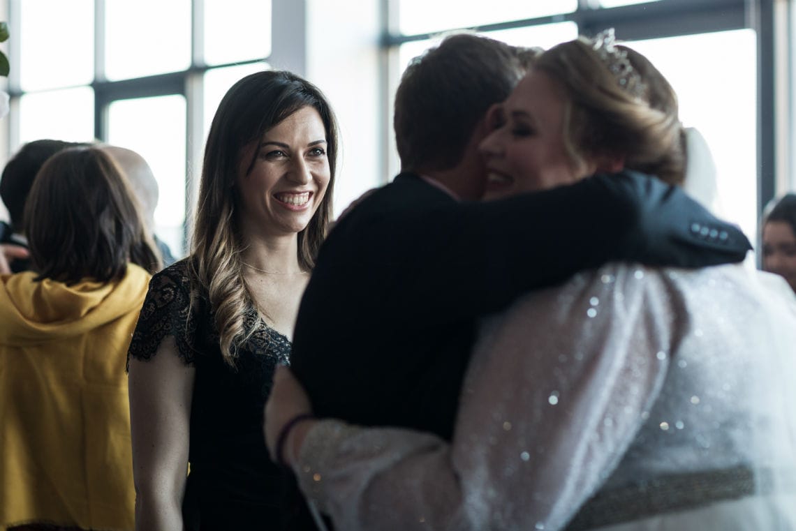 guest smiles as bride is congratulated with a hug