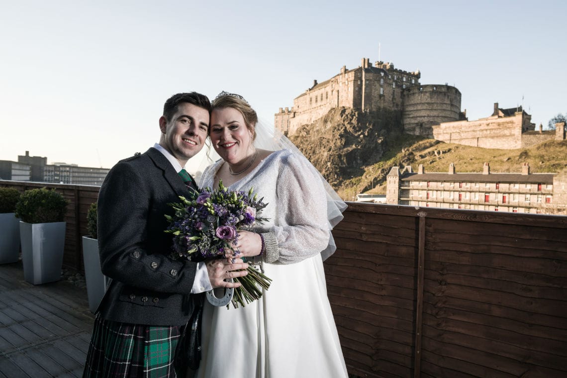 close up newlywed portrait of bride and groom on rofftop terrace with Edinburgh Castle in the background taken on Apex Hotel Grassmarket balcony