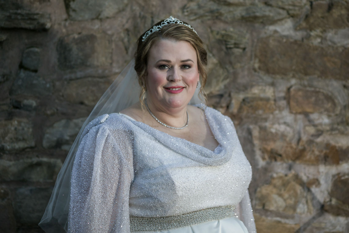 portrait of bride smiling in front of stone wall