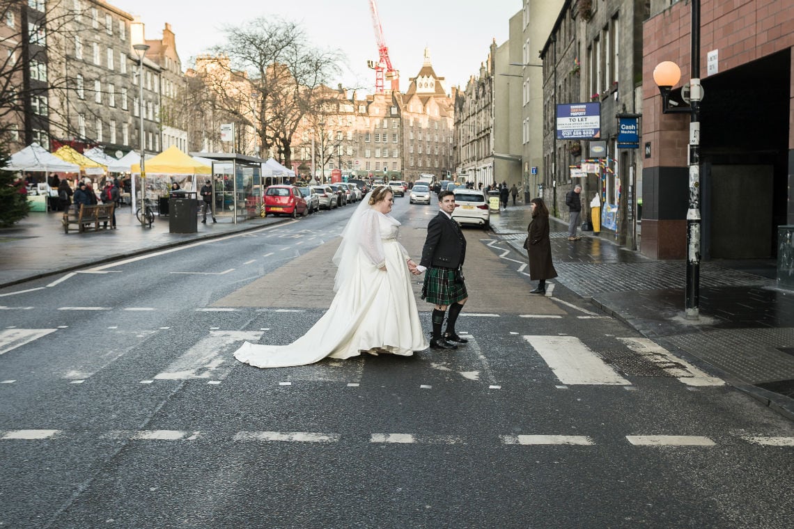 bride and groom crossing zebra crossing in Edinburgh's Grassmarket.