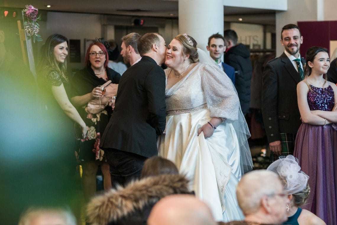 candid photo of guest kissing bride on her cheek at the drinks reception