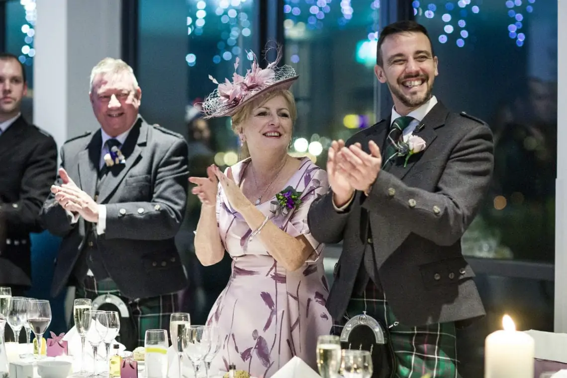 guests clapping as bride and groom are piped into the evening reception