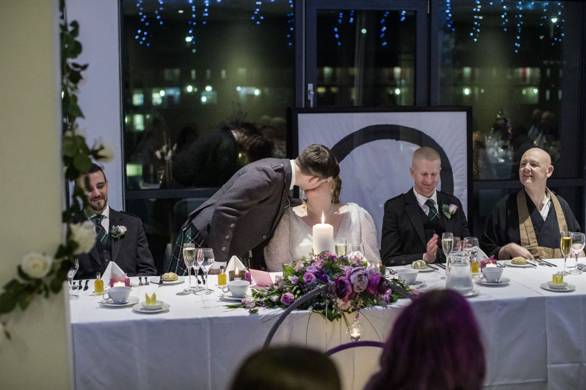 groom kissing bride at the top table