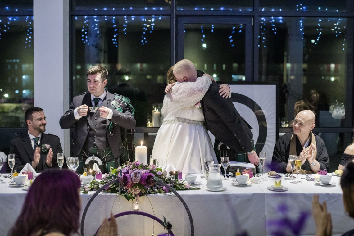 bride cuddling guest at top table