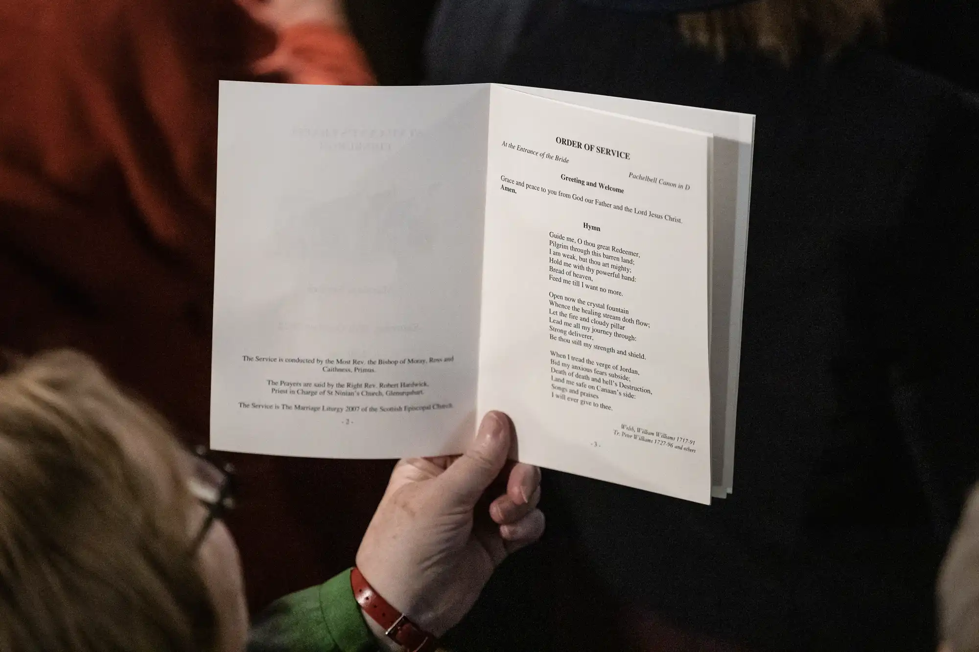 A person holds an open booklet titled "Order of Service" with text detailing a church service. The left page has introductory information, while the right page lists hymns and readings.