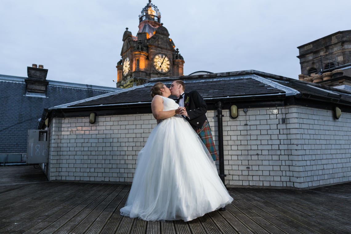 View From The Roof - newlyweds embrace with the clock tower in the background