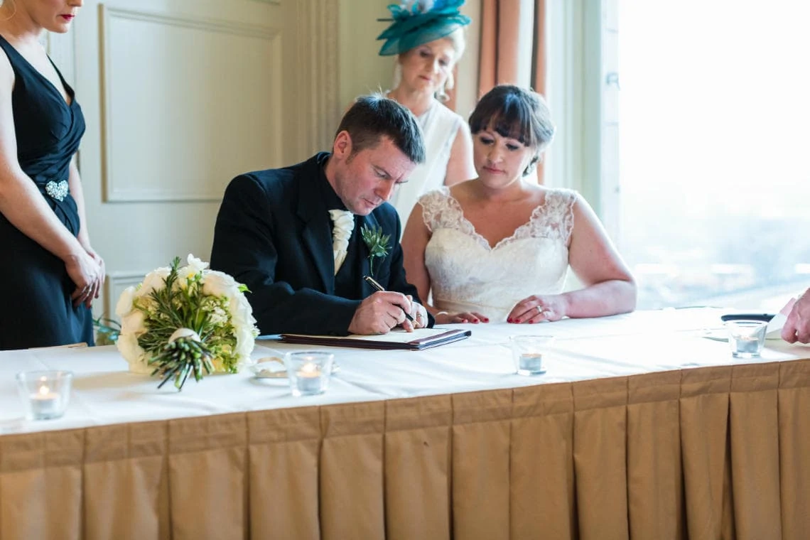 bride and groom signing the marriage schedule in the Esk Suite