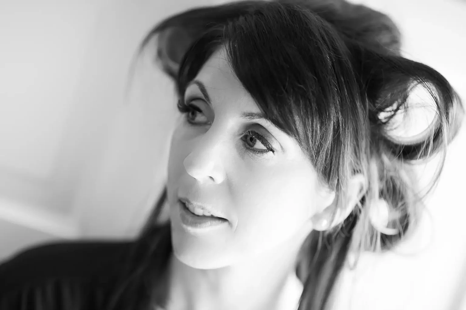 Black and white portrait of a woman with dark hair looking to the side, her hair blowing slightly.