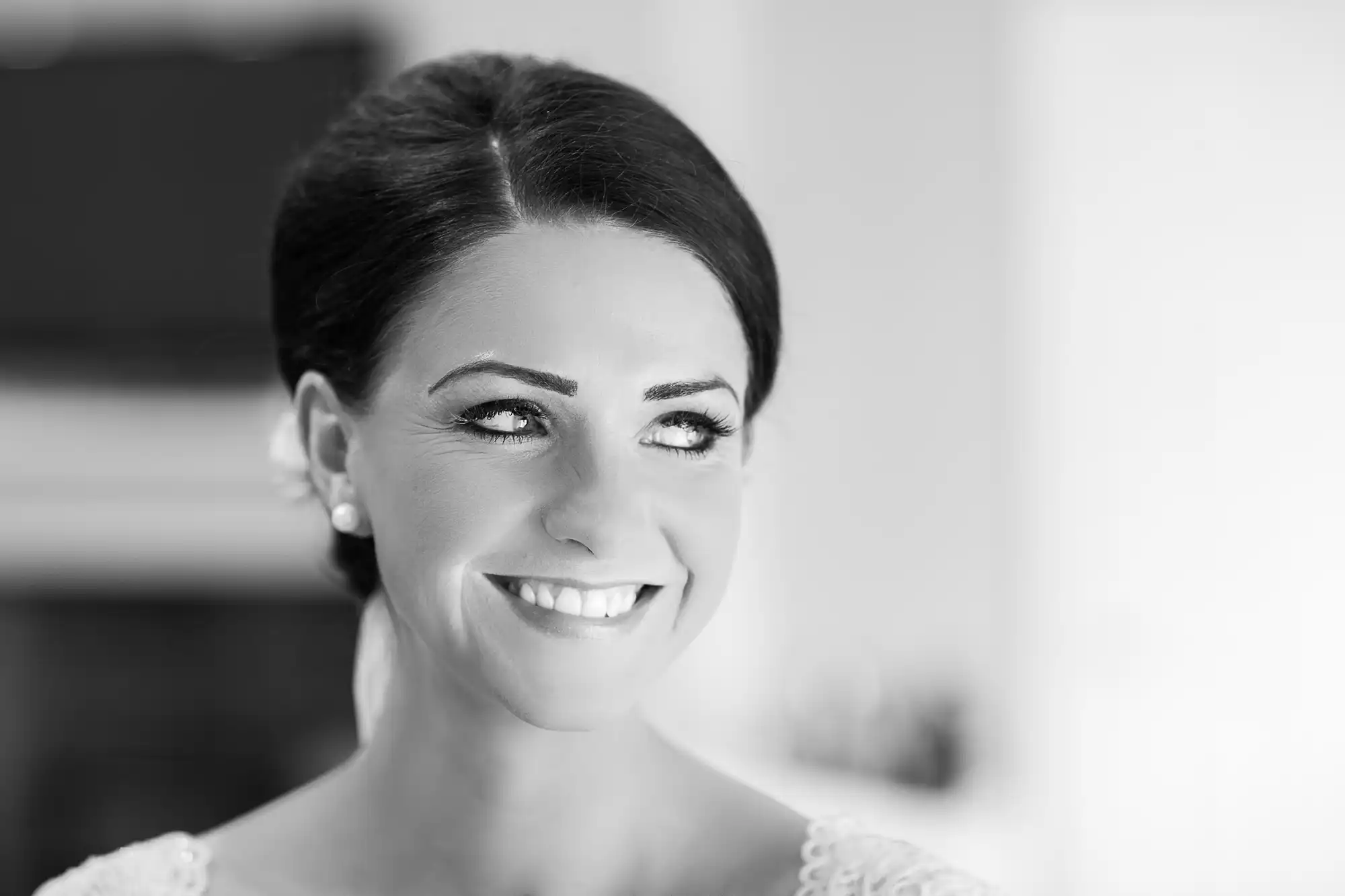 Black and white photo of a smiling woman with dark hair in an elegant updo, wearing a lacy dress.