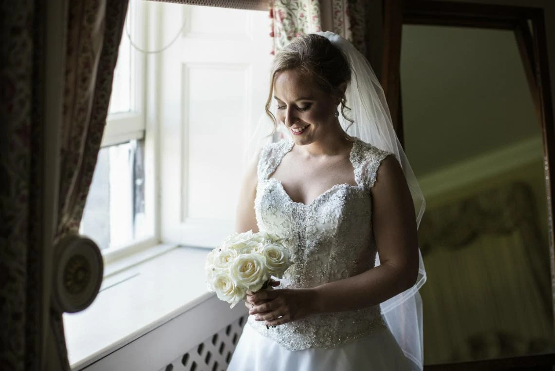 Bedroom in Main House - bride by the window looking at bouquet