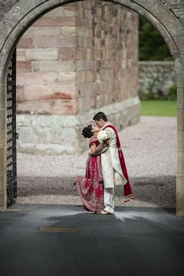 Newlyweds kiss at castle entrance