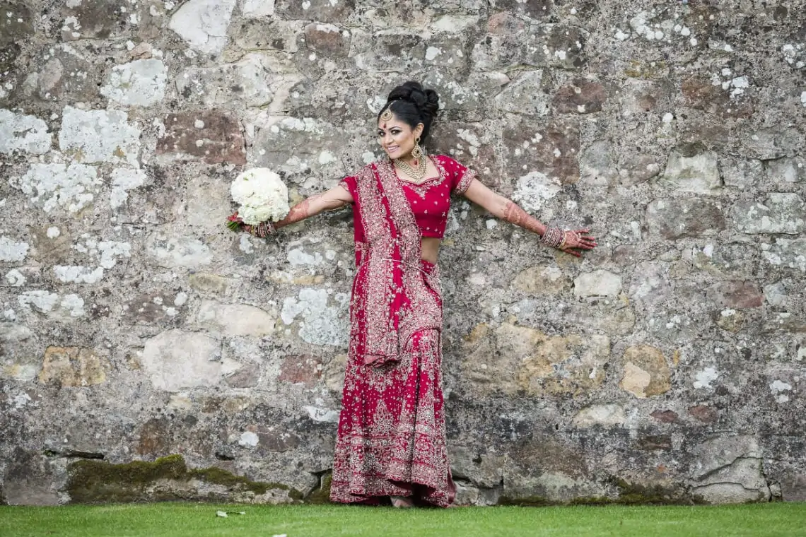 Bride standing with arms out against stone wall