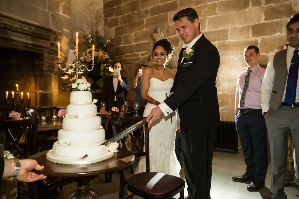 Newlyweds cutting the cake with silver sword