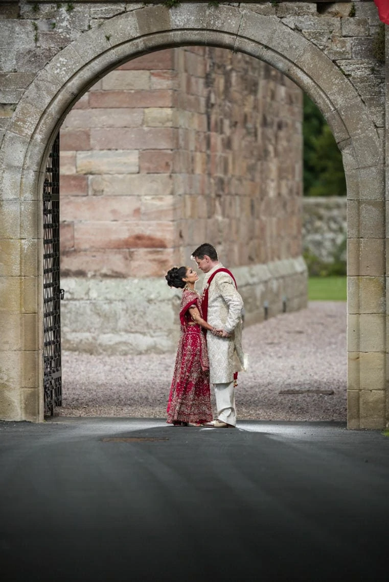 newly-weds embrace at arched entrance