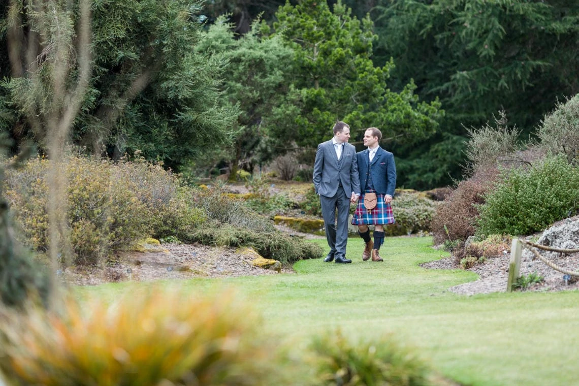 Botanic Gardens same-sex newlyweds holding hands walking across the grass