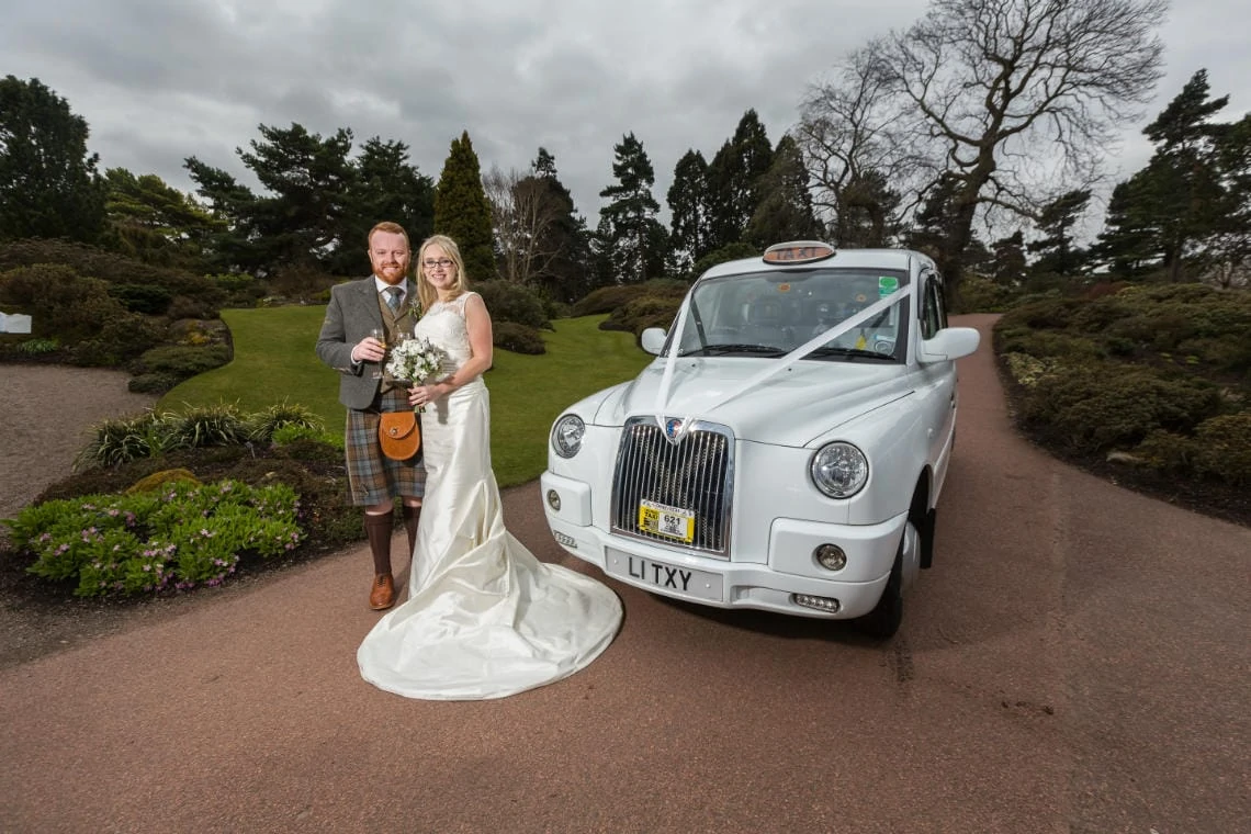 Caledonian Hall newlyweds standing beside a wedding taxi