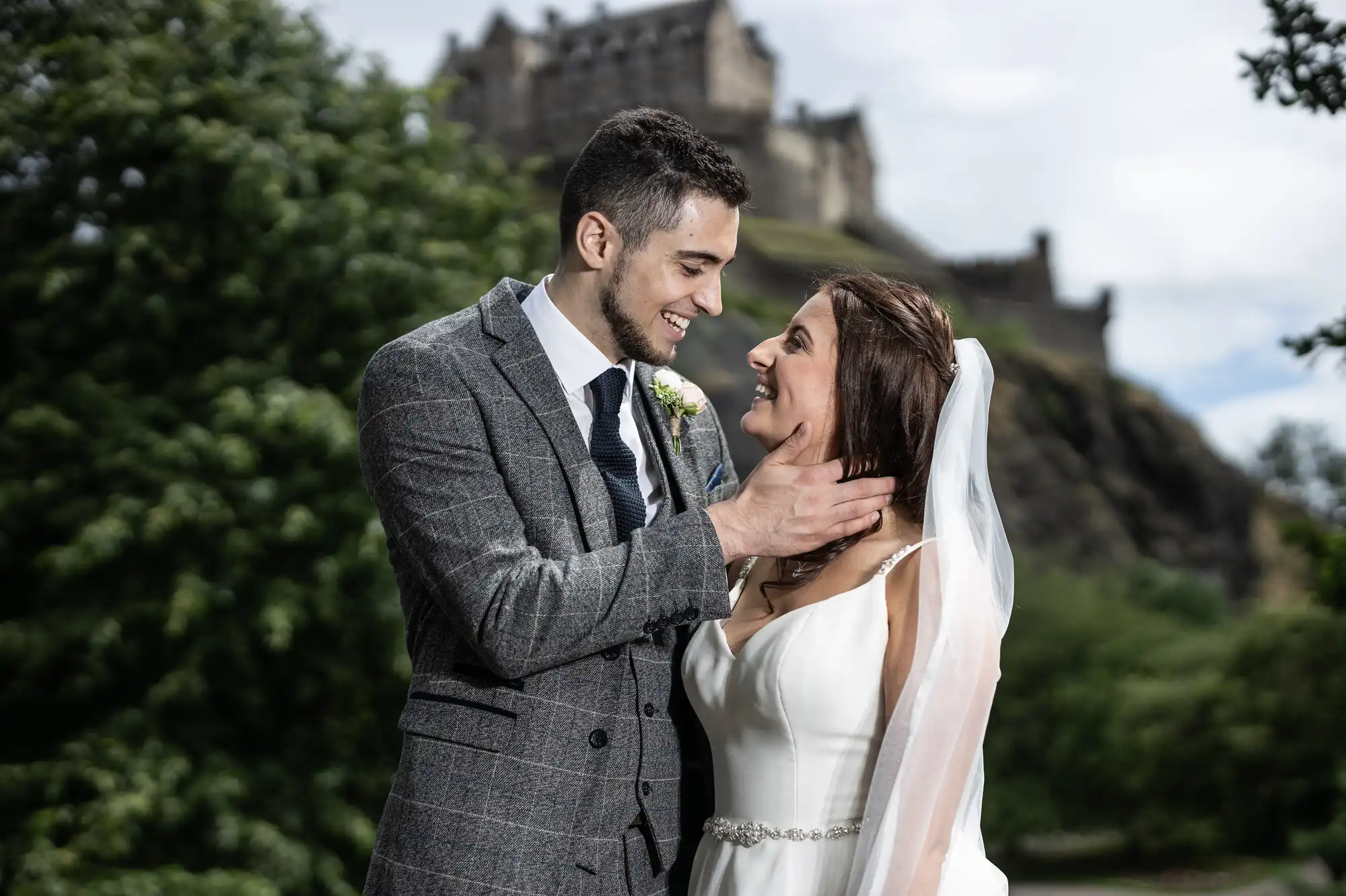 Newlyweds look at each other in Princes Street Gardens with Edinburgh Castle in the background
