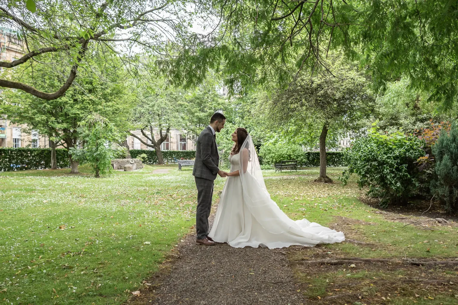 newlyweds looking at each other under trees in Princes Street Gardens