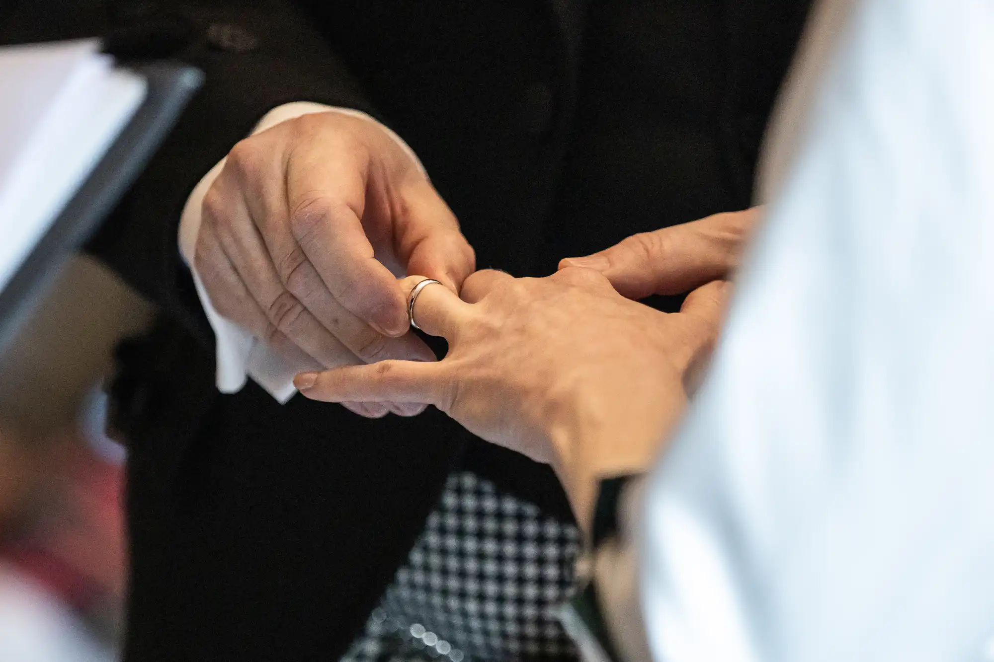 A person in a suit places a ring on another person's finger.