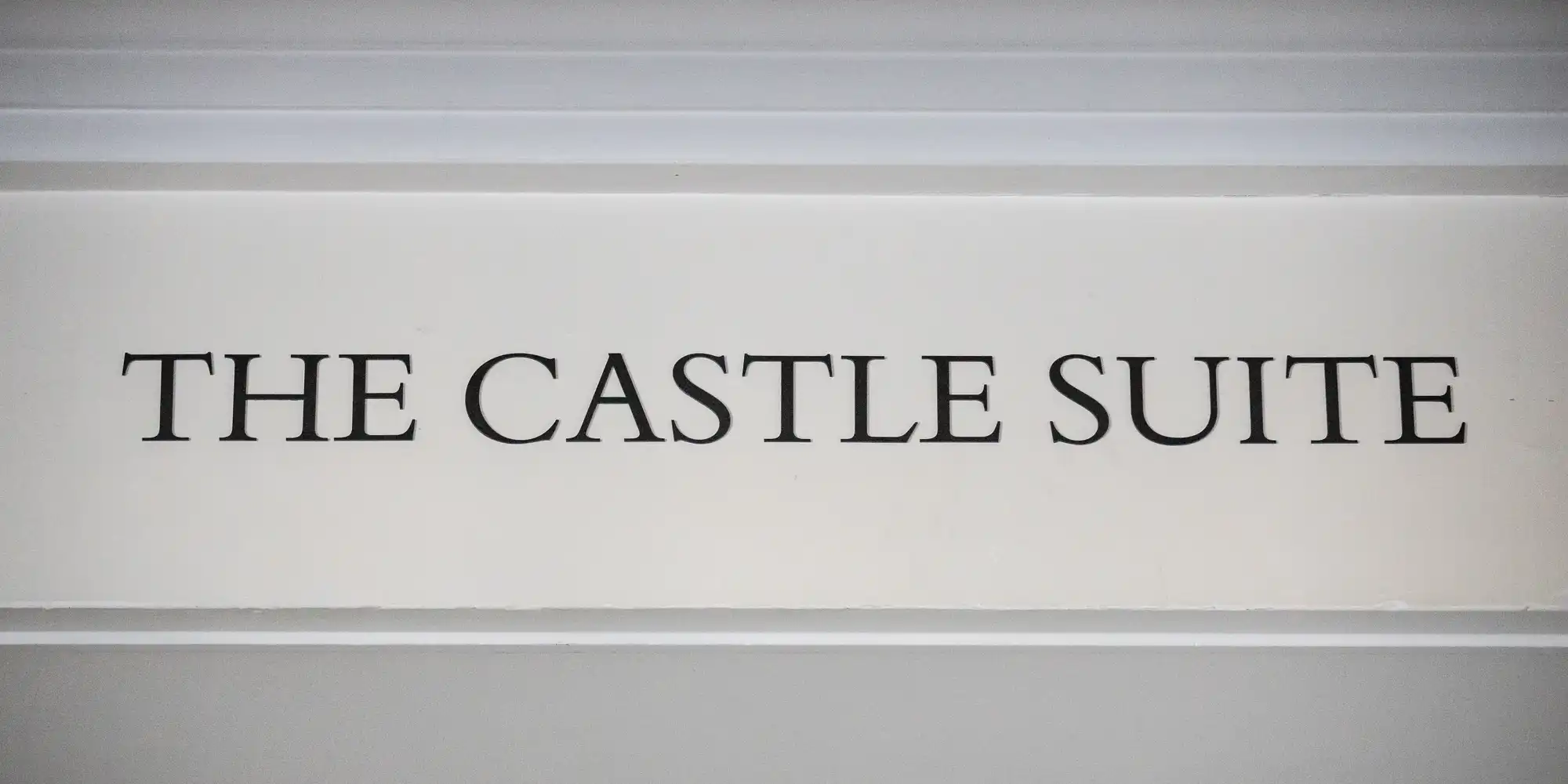 A sign reading "The Castle Suite" in black uppercase letters against a white background.