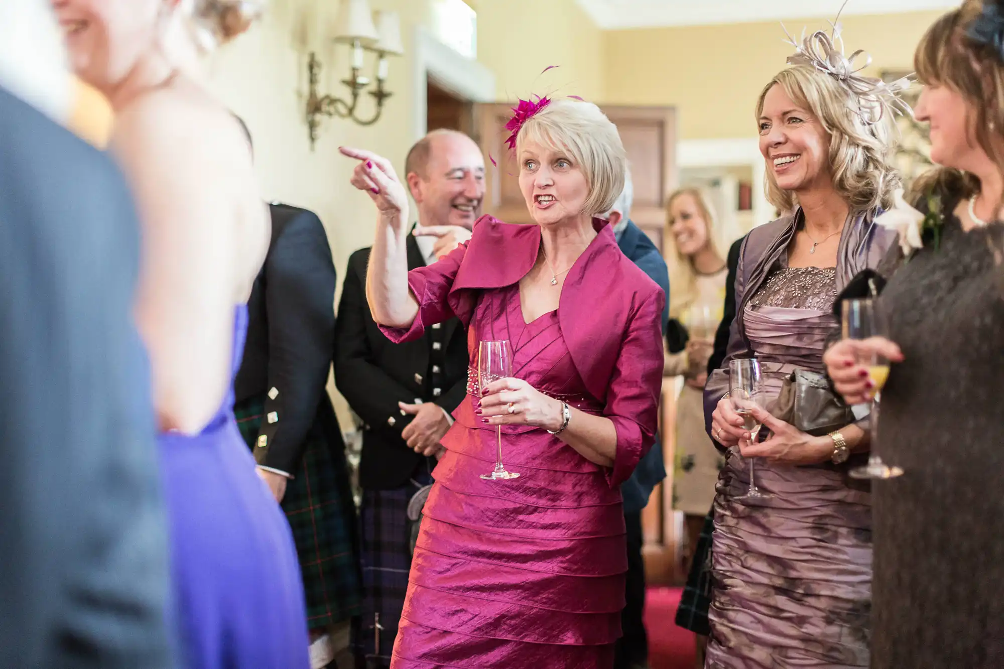 Guests in formal attire enjoying a conversation at a wedding reception, with one woman holding a champagne flute.