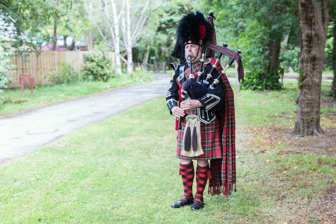 Pipe Major Iain Grant welcomes the guests