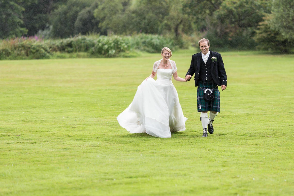 newlyweds walking across the spacious lawn
