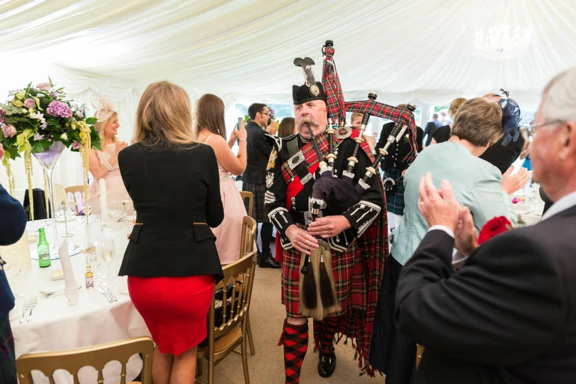 Pipe Major Iain Grant leads the newlyweds to the top table in The Pavilion