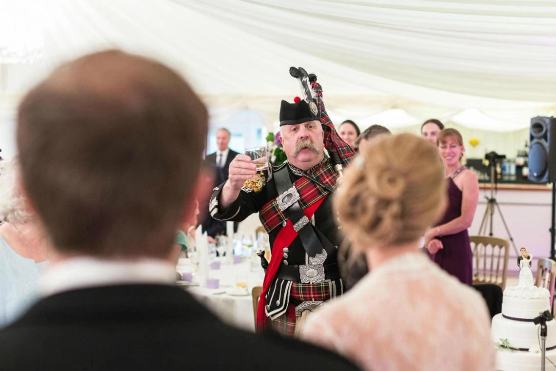 Pipe Major Iain Grant raises a toast to the newlyweds in The Pavilion
