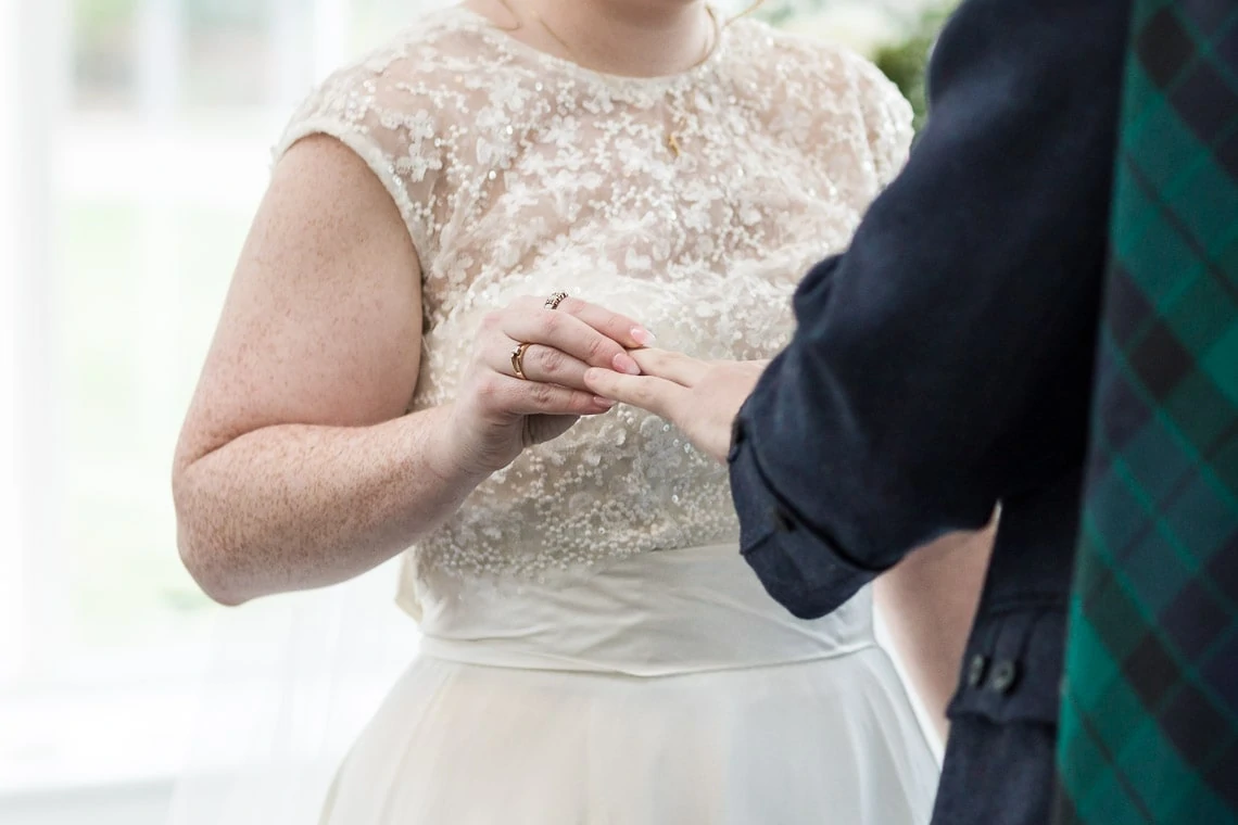 bride places ring on groom's finger