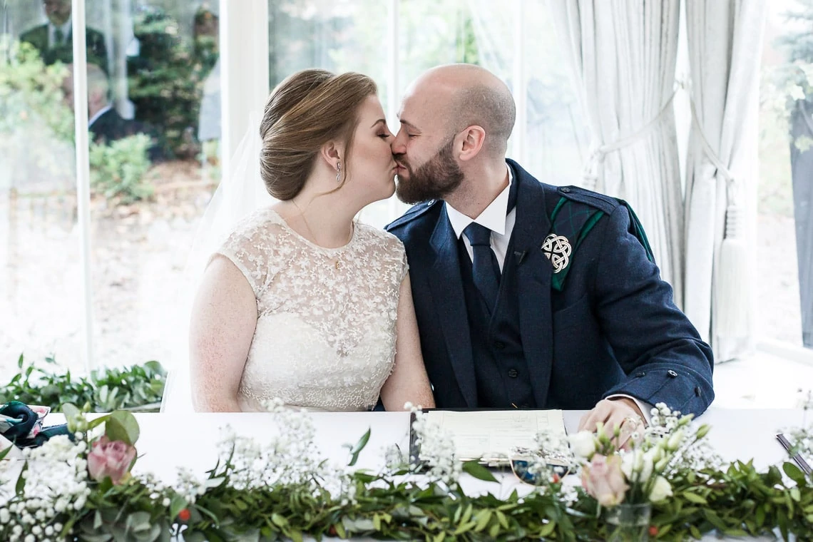 newlyweds kissing during signing of the marriage schedule