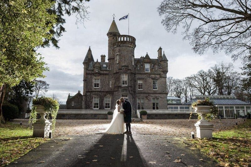 Carlowrie Castle wedding photographers - newlyweds backlit in front of the castle