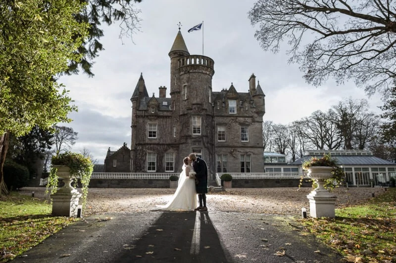 Carlowrie Castle wedding - newlyweds backlit in front of the castle